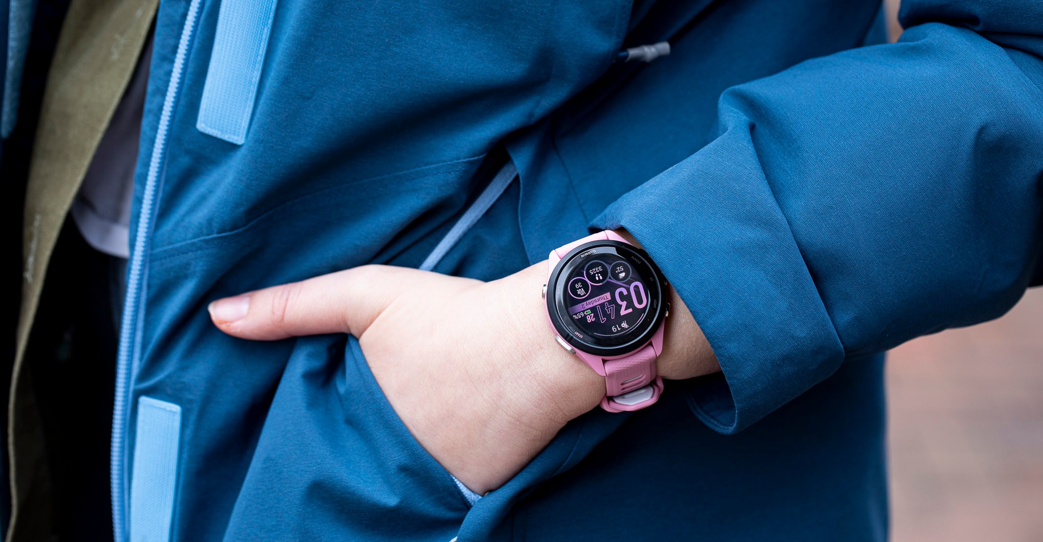 Close-up of the Garmin Forerunner 265S on the wrist of a person putting their hand into a jacket pocket.