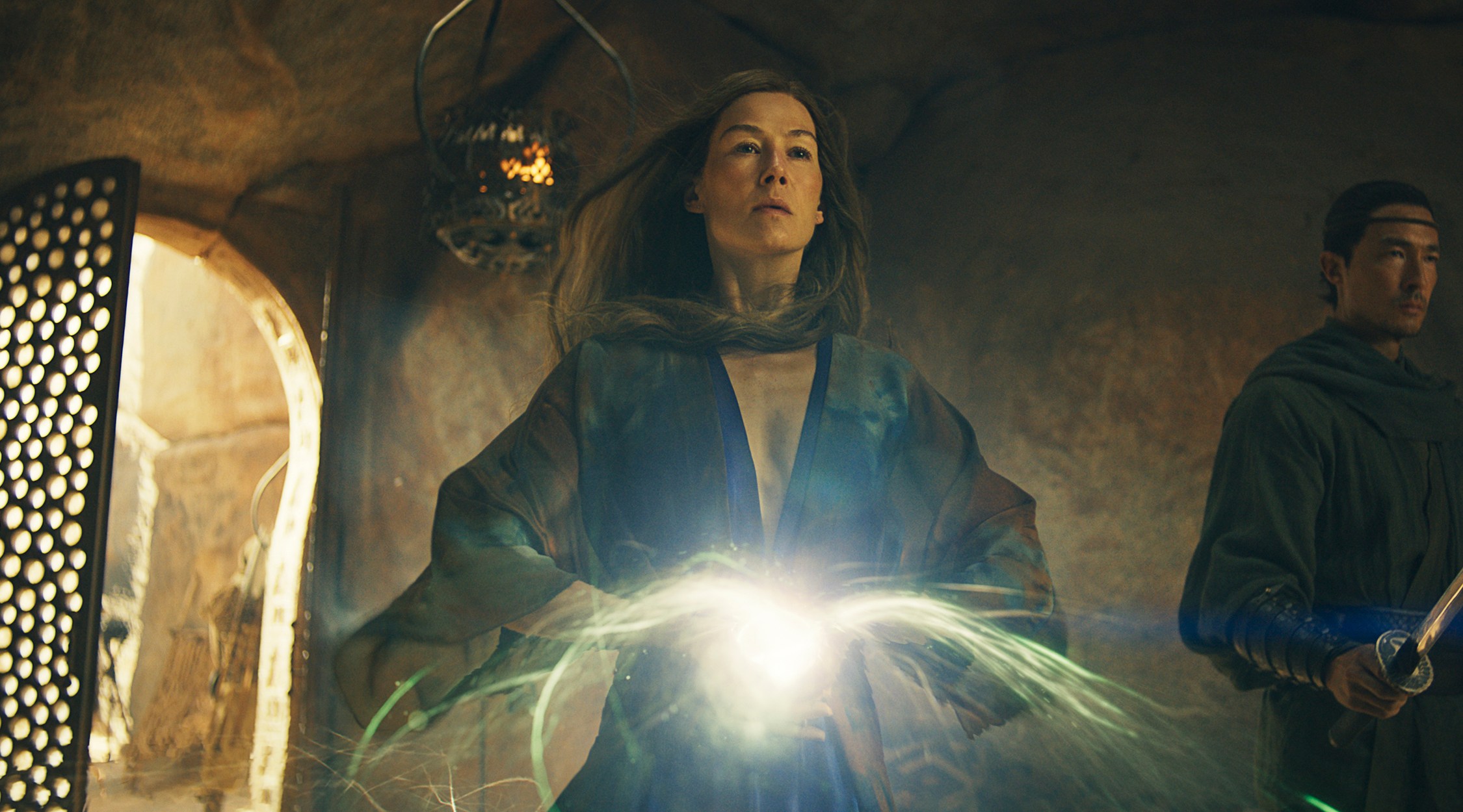 A woman in a flowing blue robe holding her hands together to summon a ball of light.