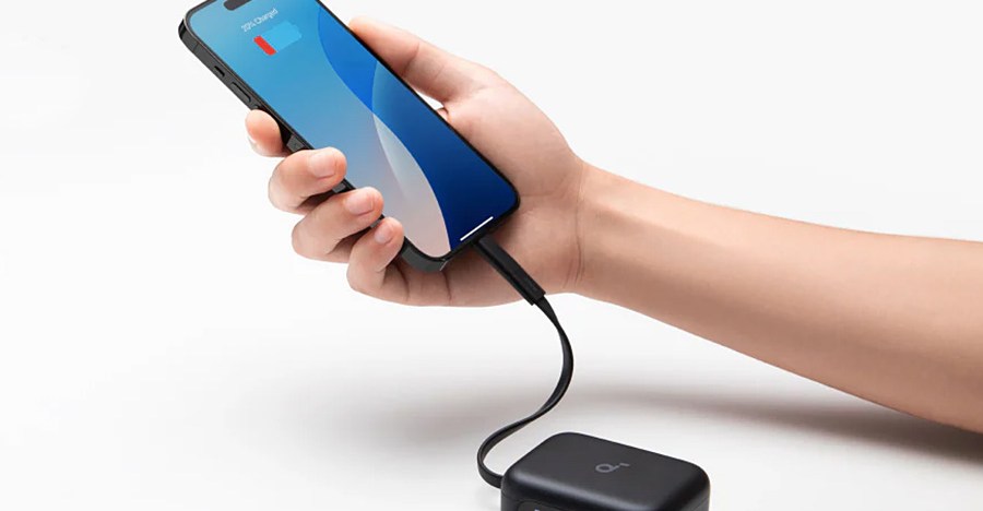 A hand holds a smartphone that’s connected by a short USB-C cable to Anker’s new Soundcore P41i wireless earbuds’ charging case.