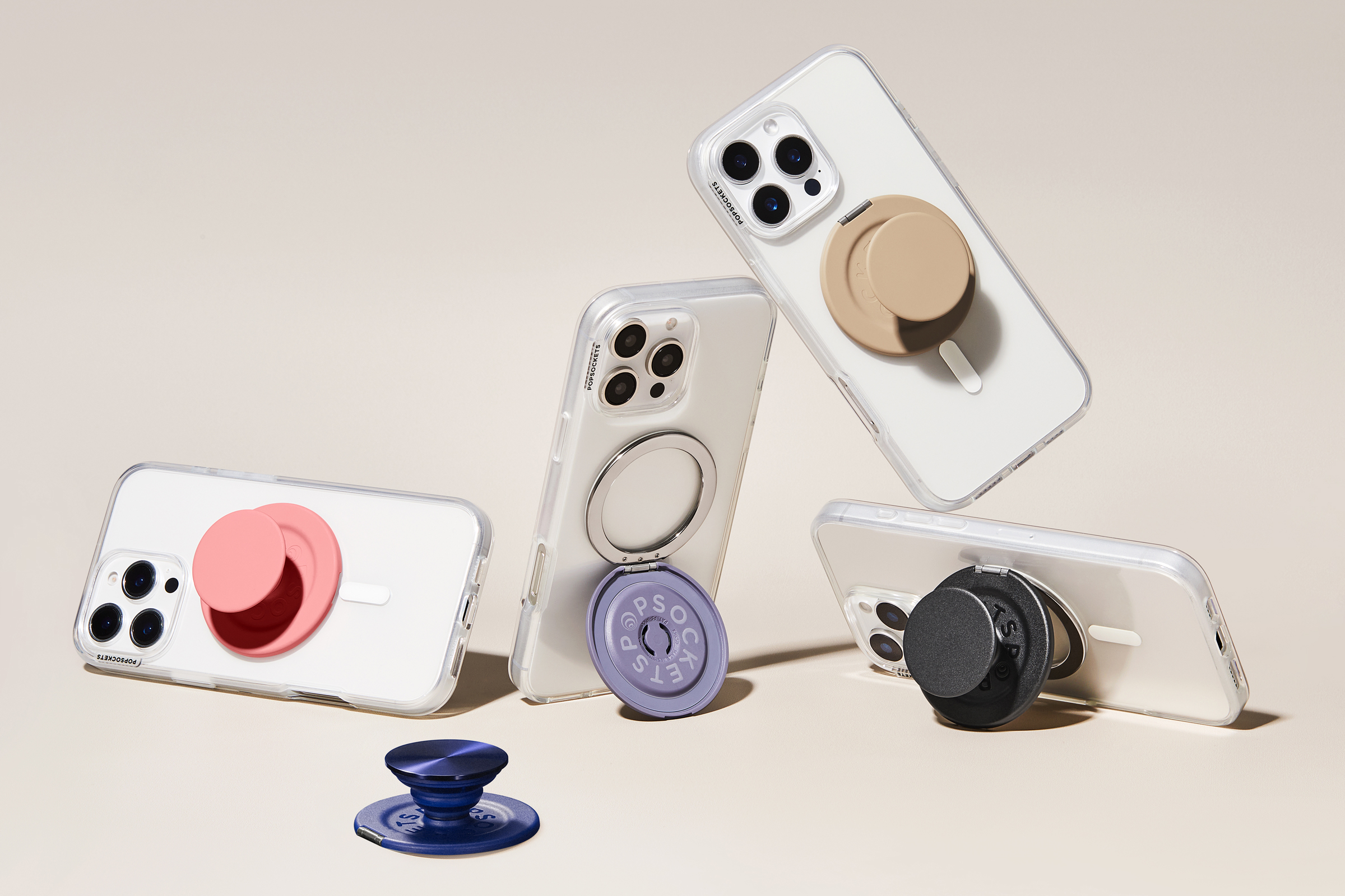 Several smartphones featuring PopSockets’ new Kick-Out Grip and Stand attached.