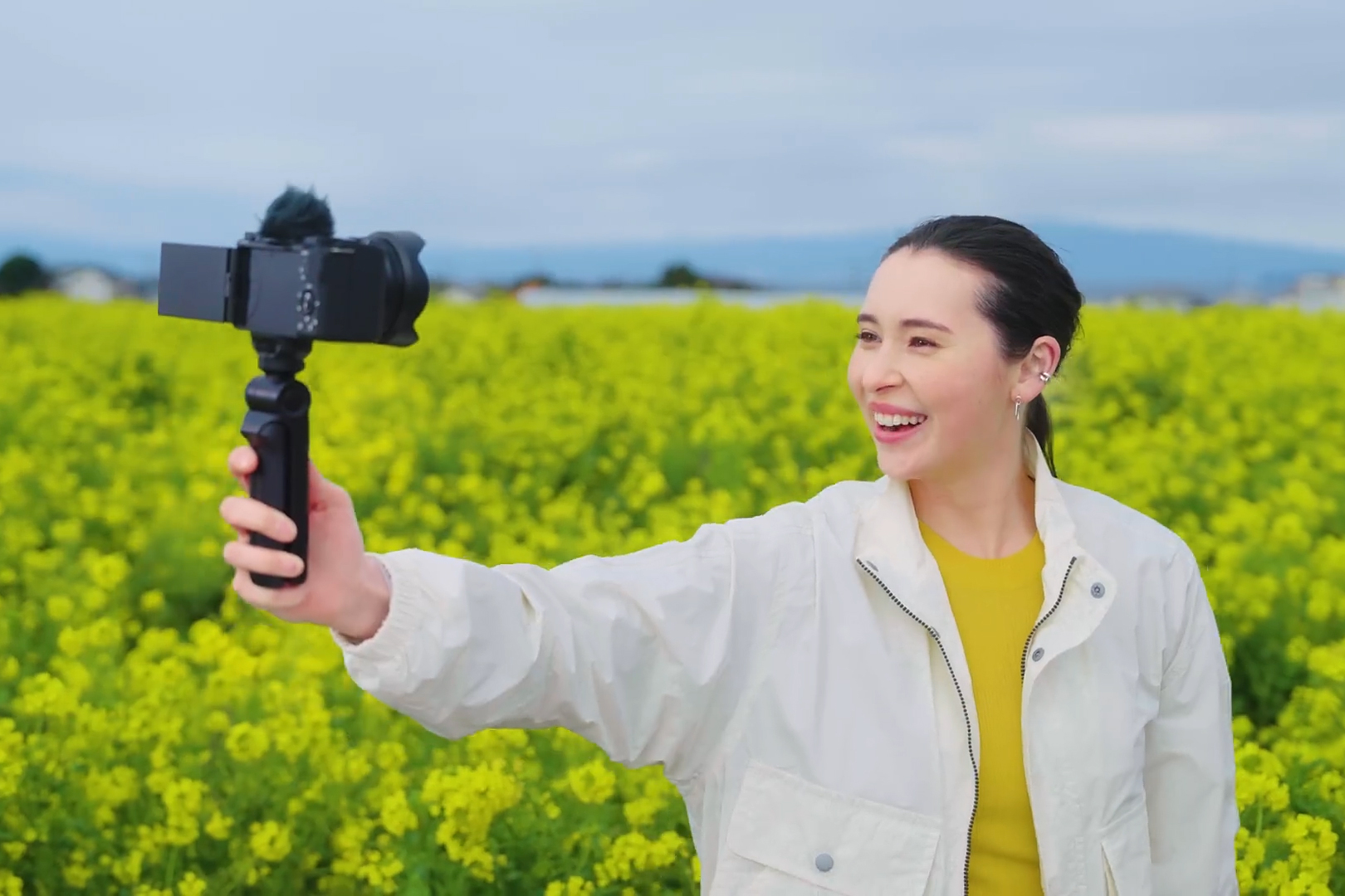 A person using Sony’s GP-VPT3 grip to film themselves in a lush field.