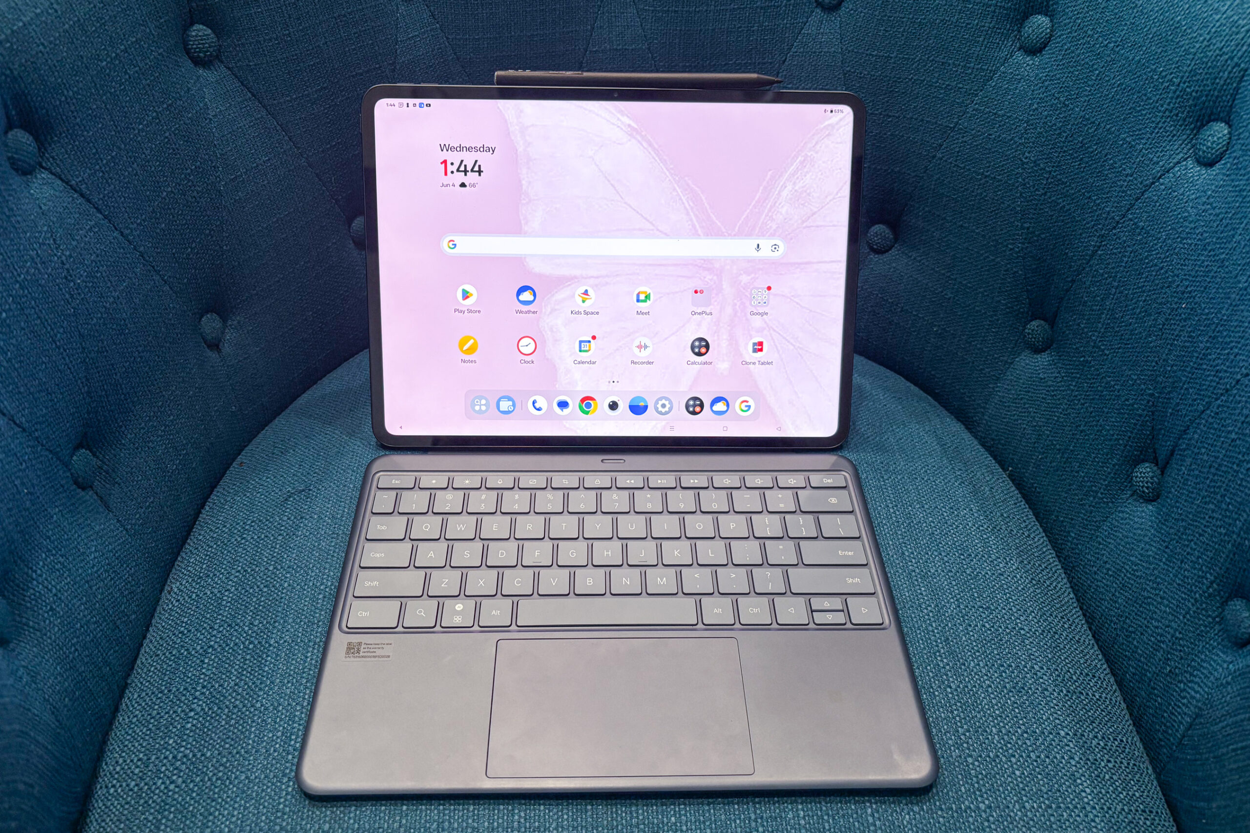 The OnePlus Pad 3, attached to its Smart Keyboard, rests on a blue couch.
