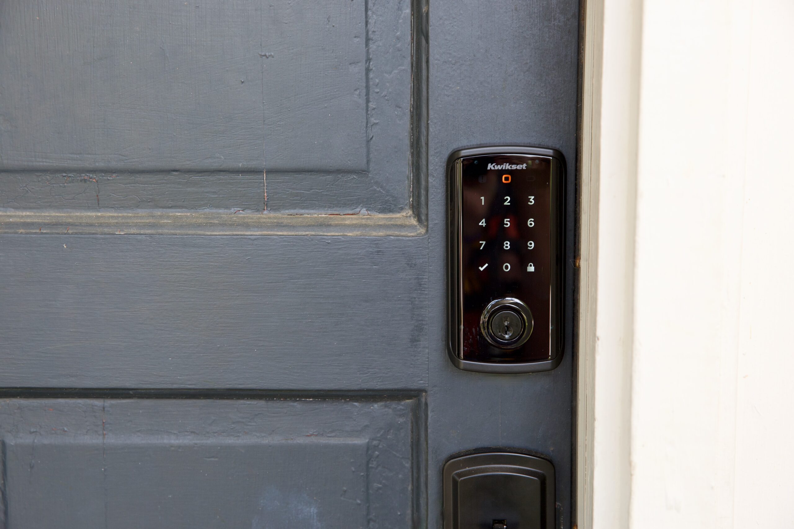 A black smart lock on a blue door.