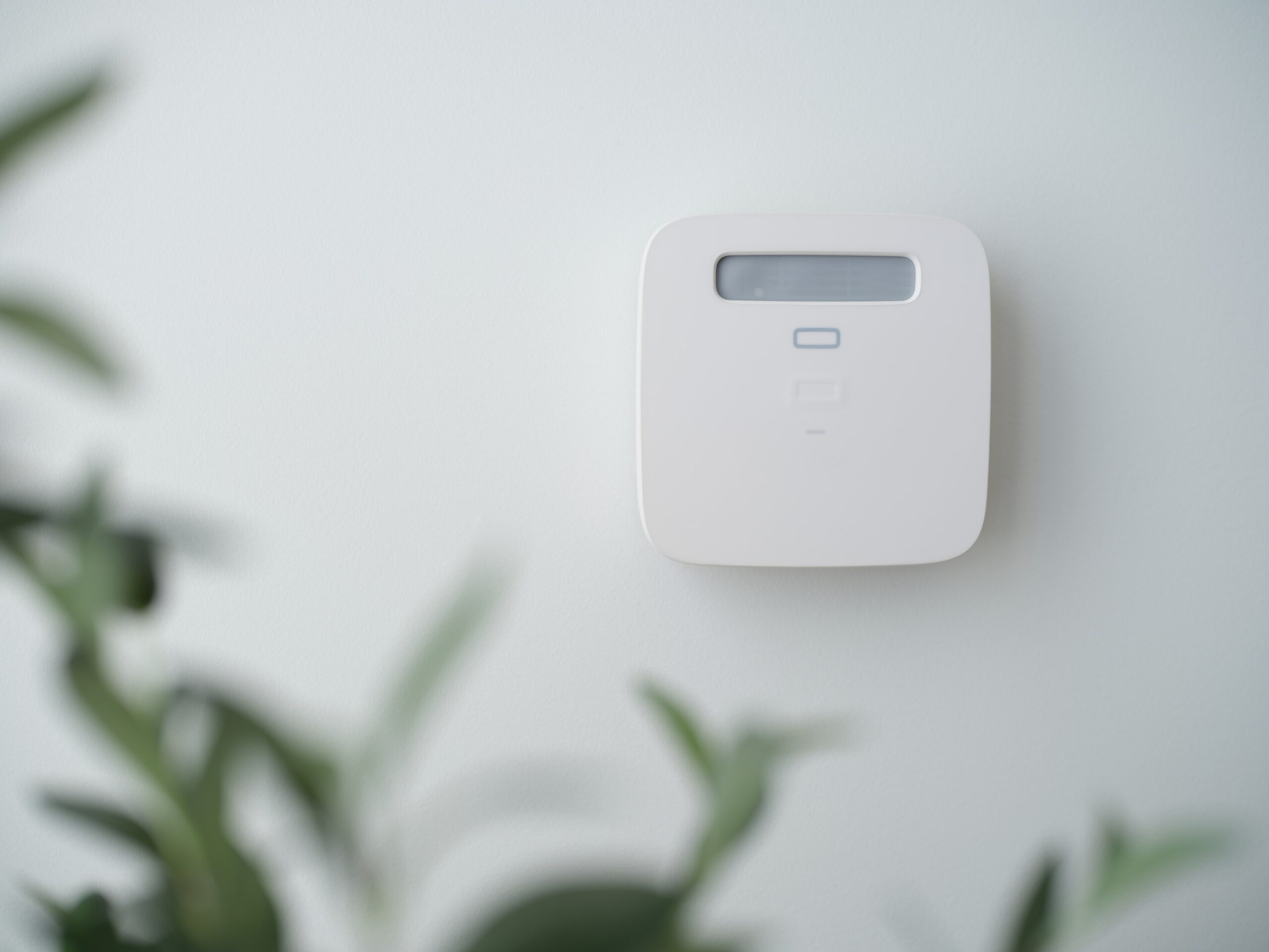 A white smoke alarm on a white wall.