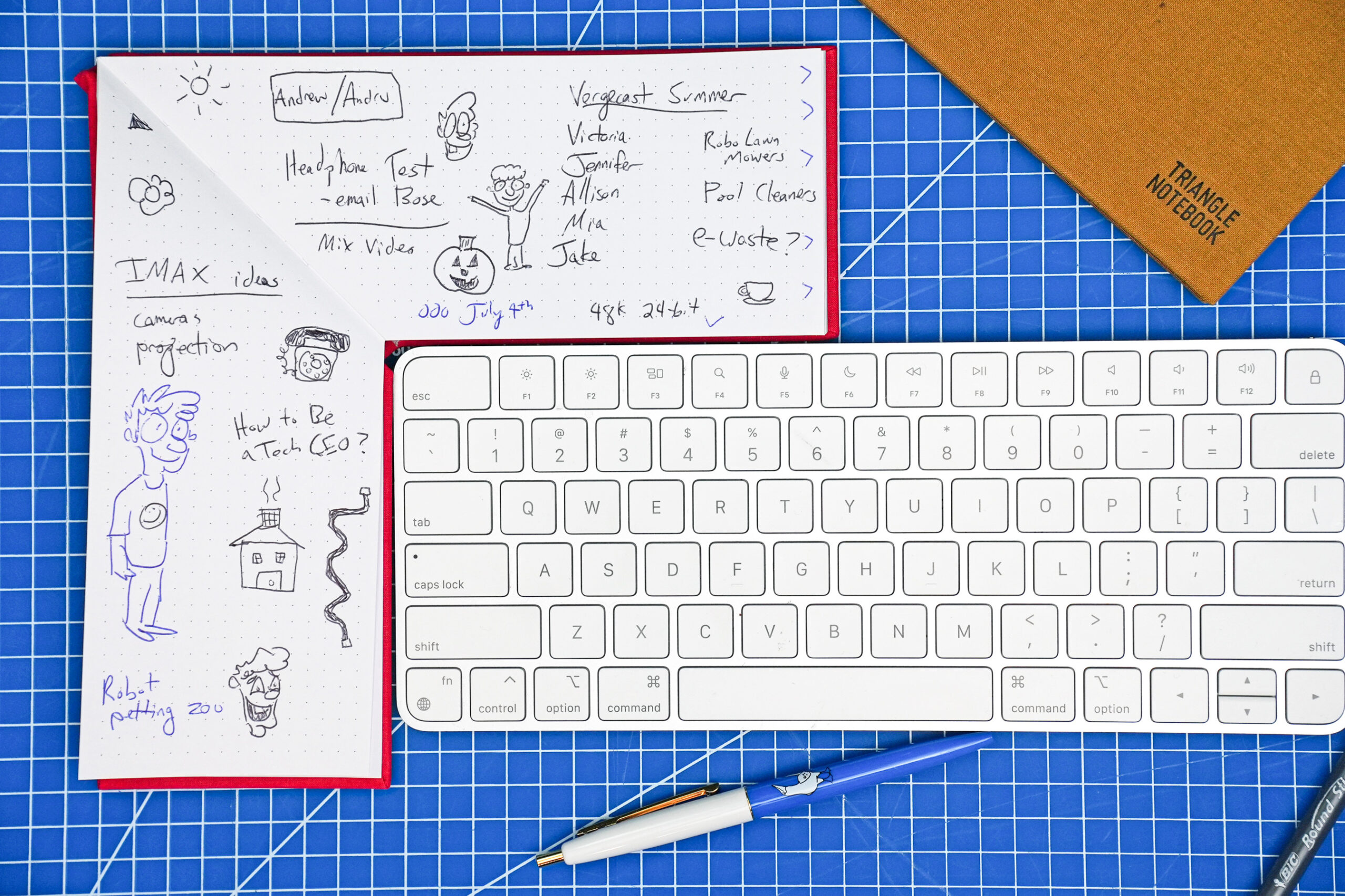 White keyboard with L-shaped notebook wrapped around it. the notebook is filled with doodles.