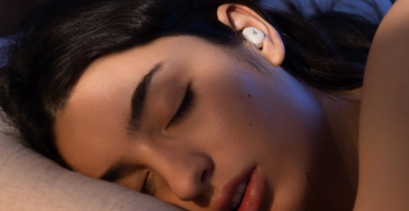 A person asleep in bed wearing one of Anker’s Soundcore Sleep A30 wireless earbuds in their ear.