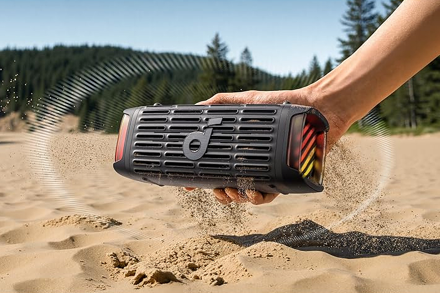 A hand holding Anker’s Boom 3i speaker as it vibrates to shake off sand.