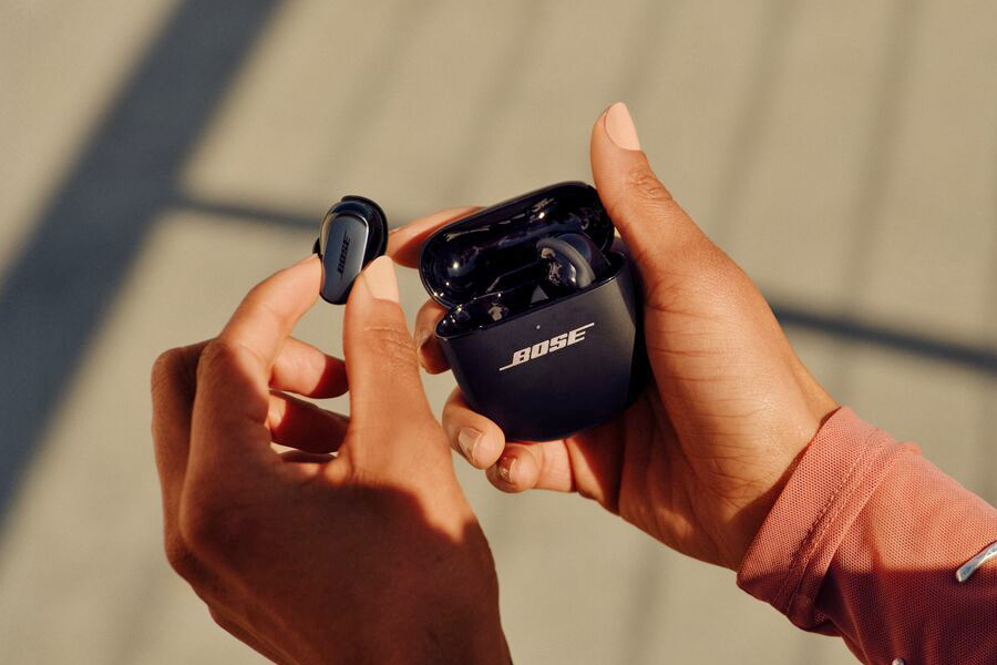 A hand removing a single earbud from a wireless earbud charging case.