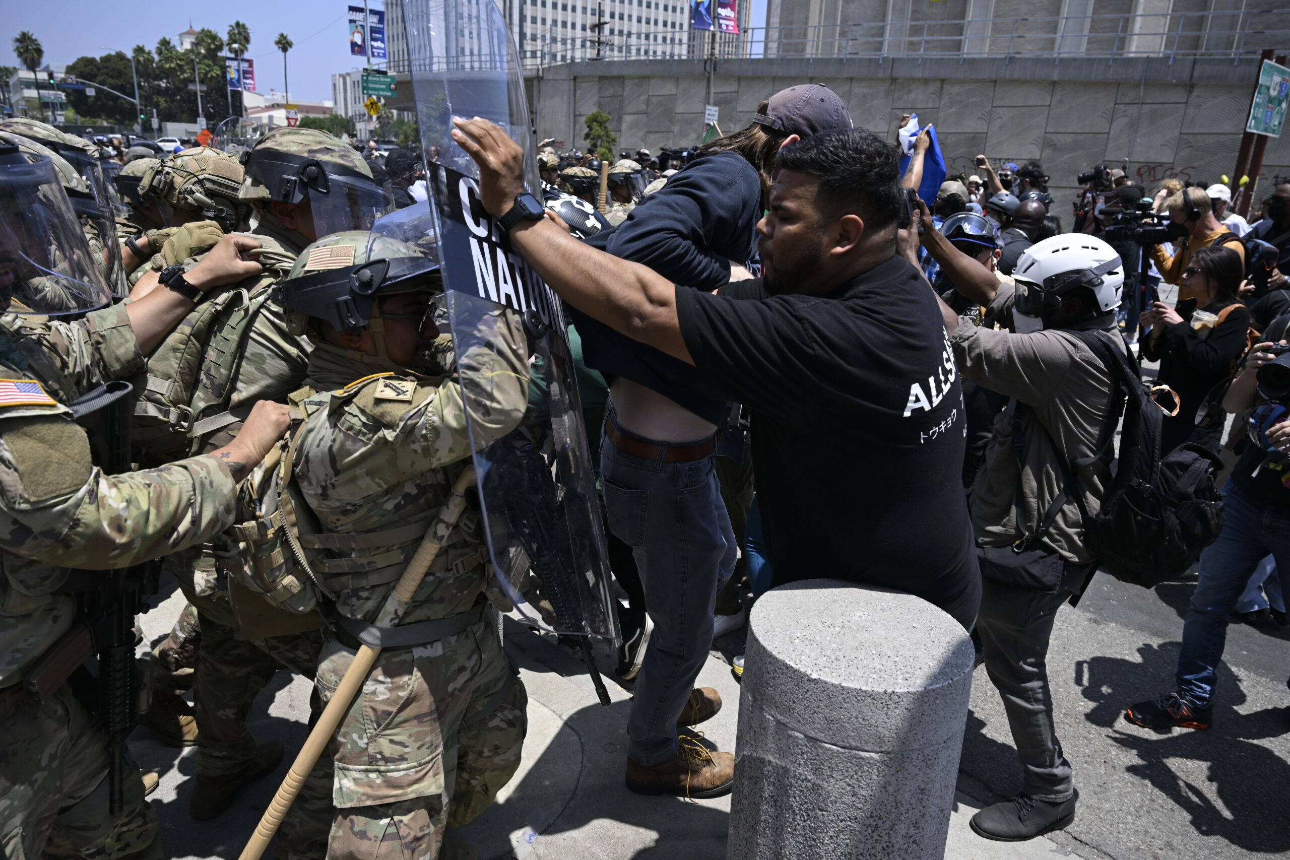 A crowd of uniformed officers struggle with protestors in a crowd scene.