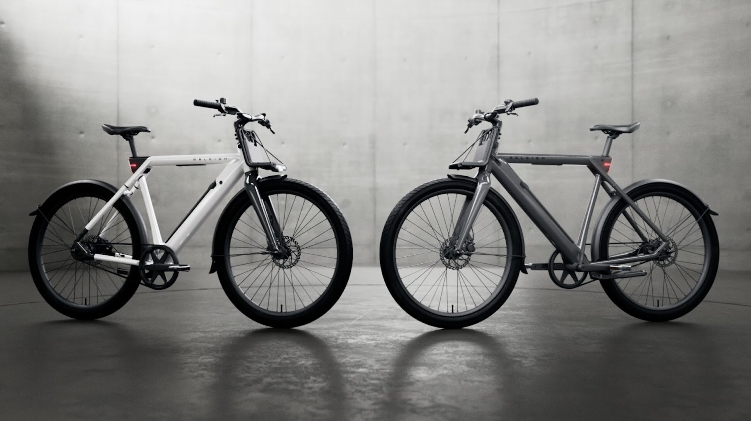 Two e-bikes with lights on shown in full side profile facing each other.