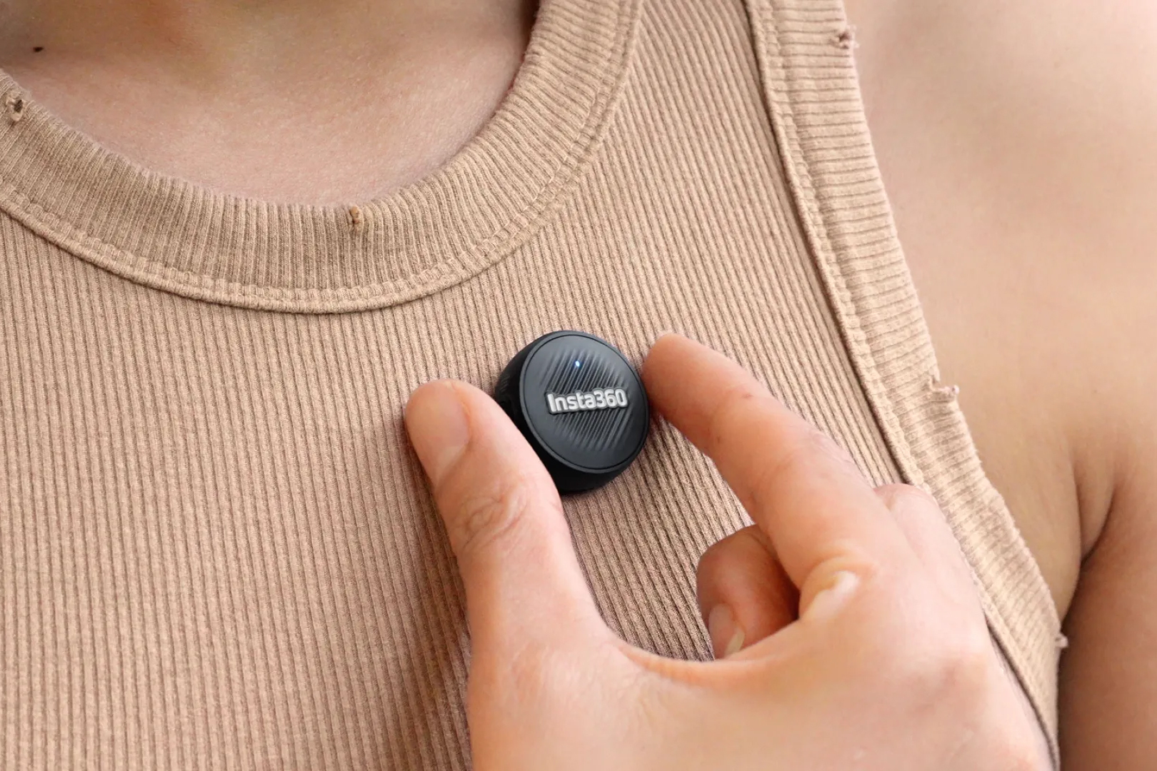 A person attached the Insta360 Mic Air wireless microphone to their shirt.