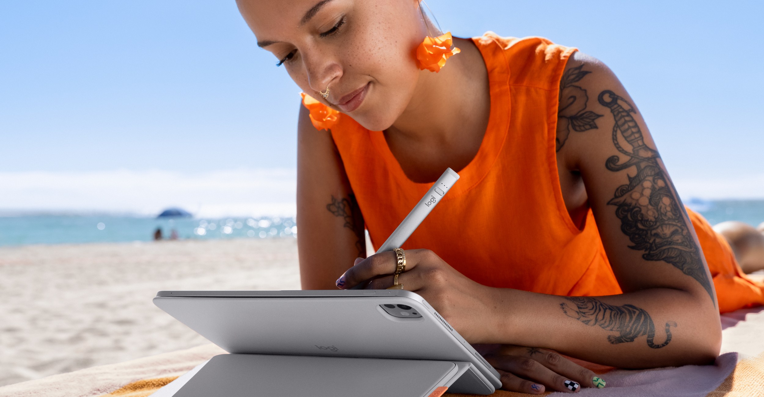 A person lying on a beach chair using a stylus on a propped up iPad.