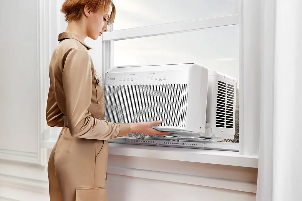 A person installs Midea’s U-shaped air conditioner in a window.