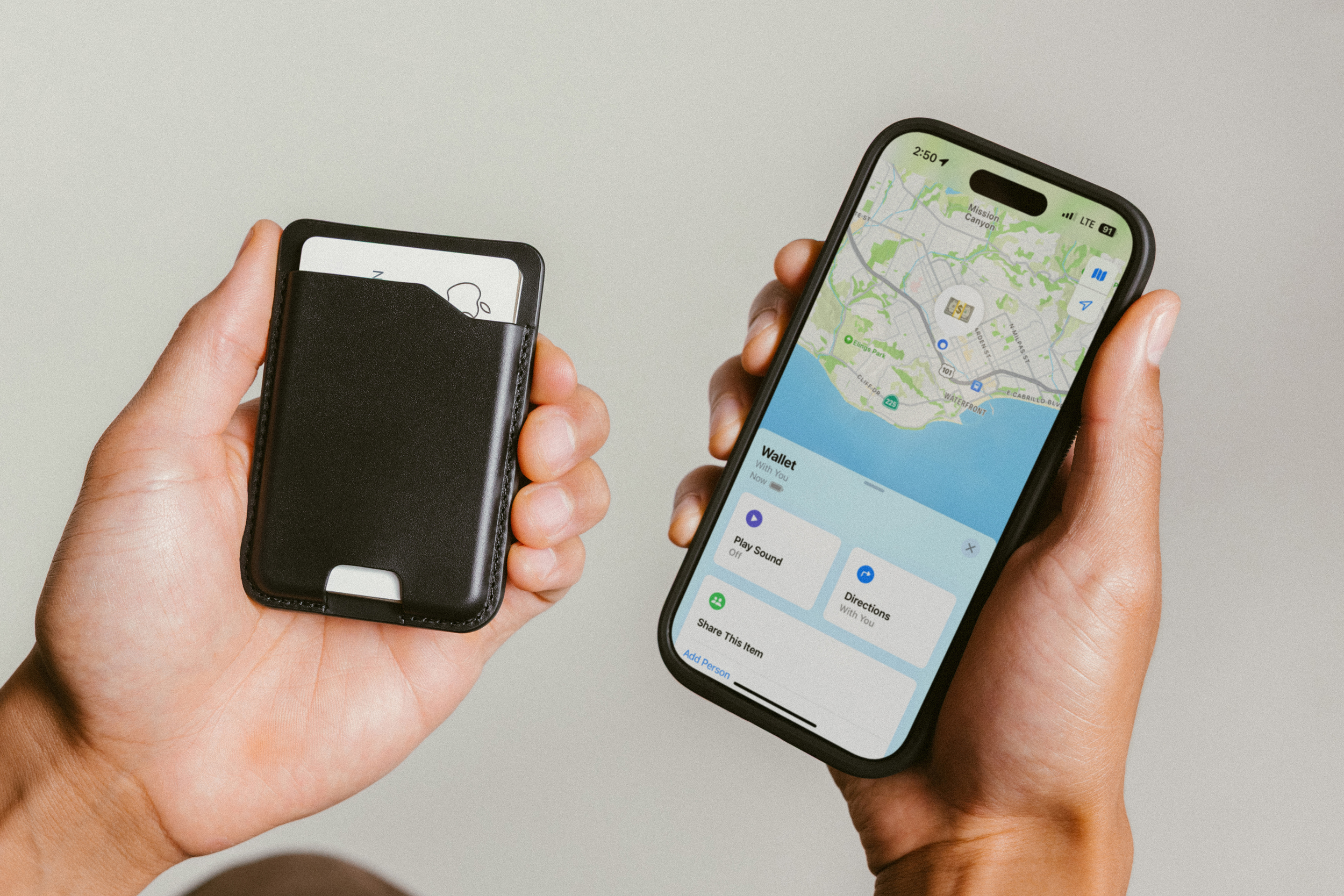A hand holds a leather Nomad wallet next to an iPhone with Apple’s Find My app open.