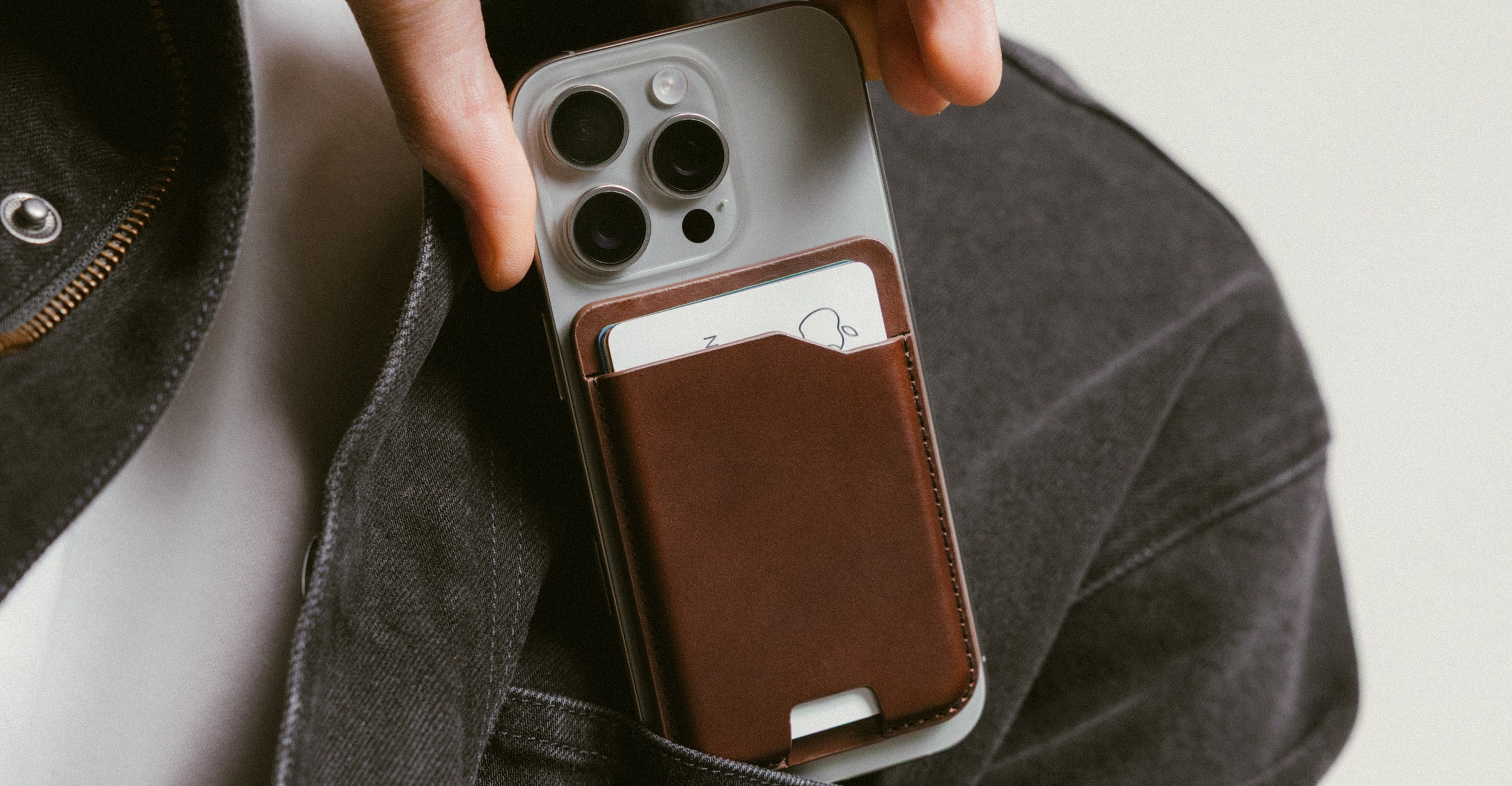 An iPhone with a Nomad MagSafe wallet attached is slid into a pocket.