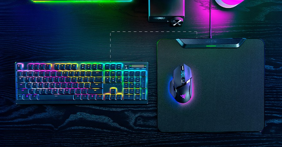 An overhead view of Razer’s HyperFlux V2 Wireless Charging System on a black wooden desk next to a keyboard.