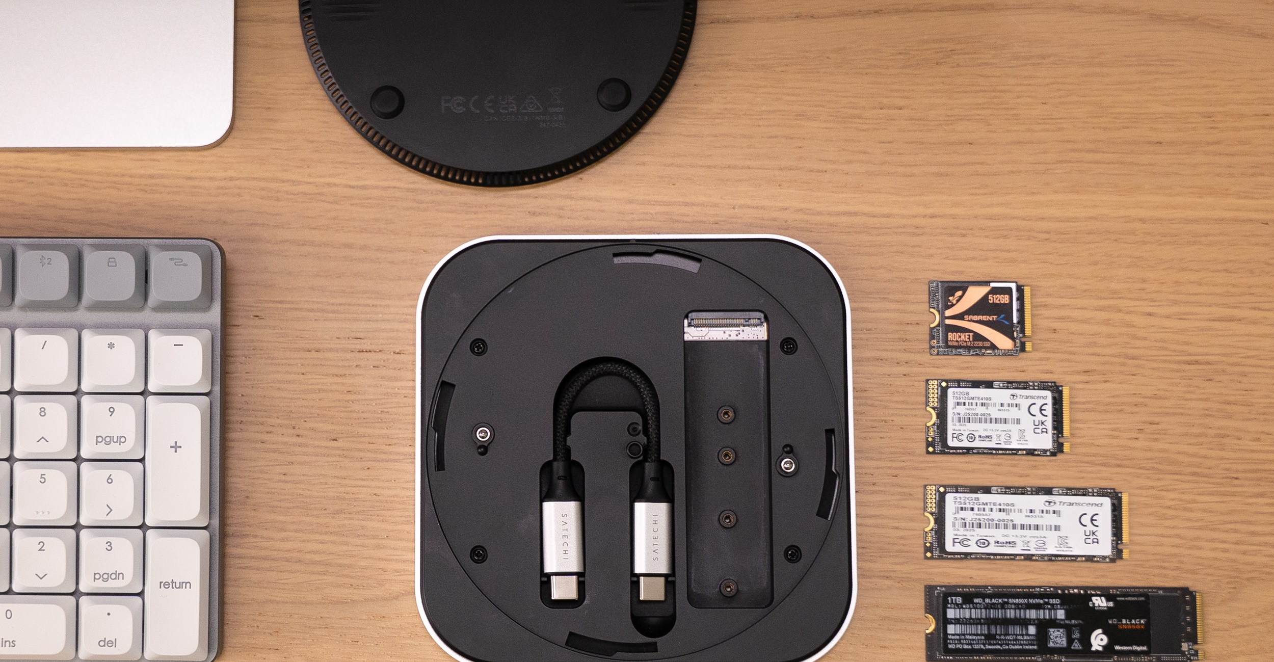 Satechi’s USB4 SSD enclosure pictured upside down on a wooden desk with several SSD drives next to it.