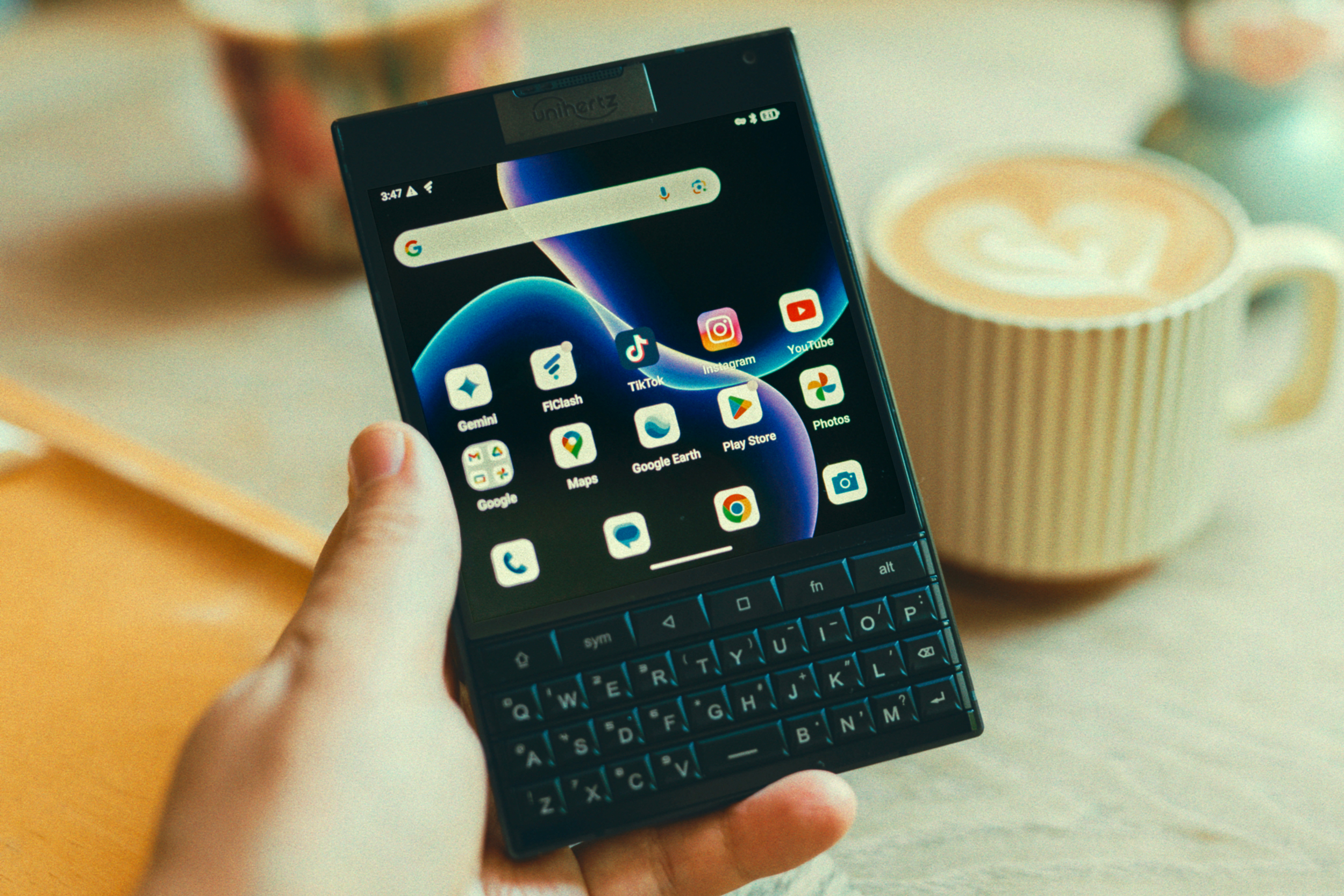 A hand holding the Unihertz Titan 2 smartphone over a breakfast table.