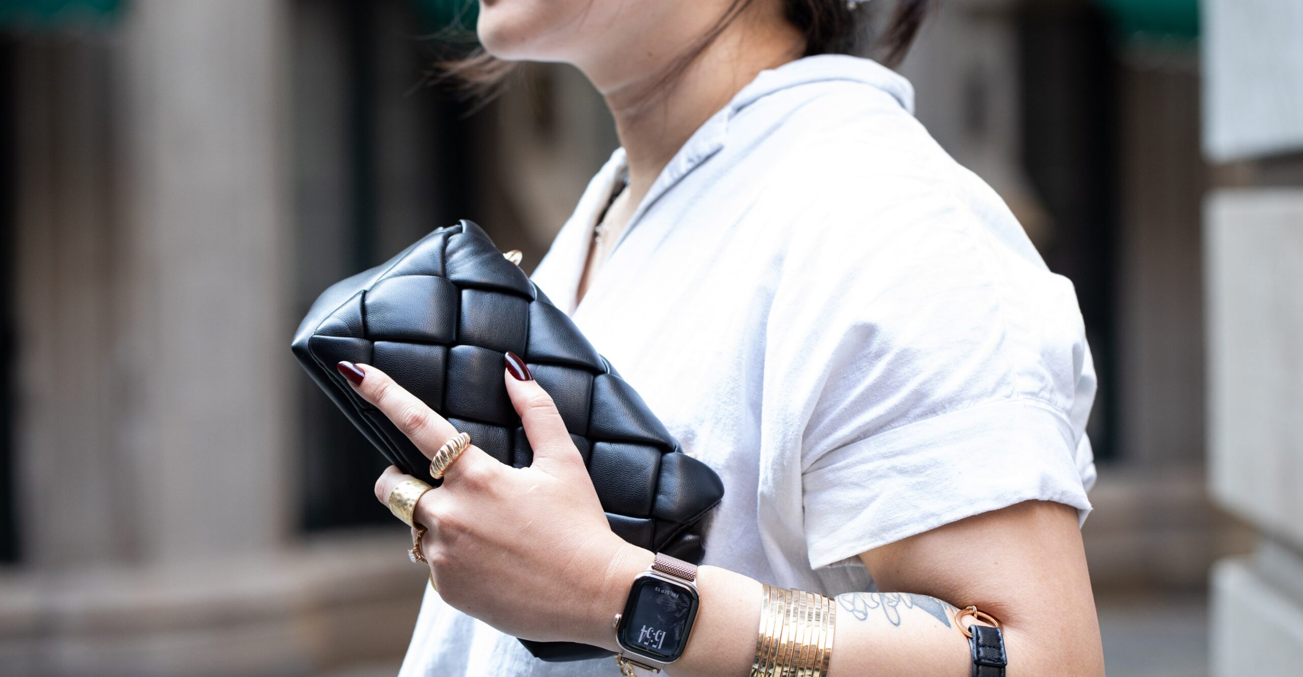 Person wearing gold Apple Watch Series 10 in titanium while wearing lots of matching accessories.