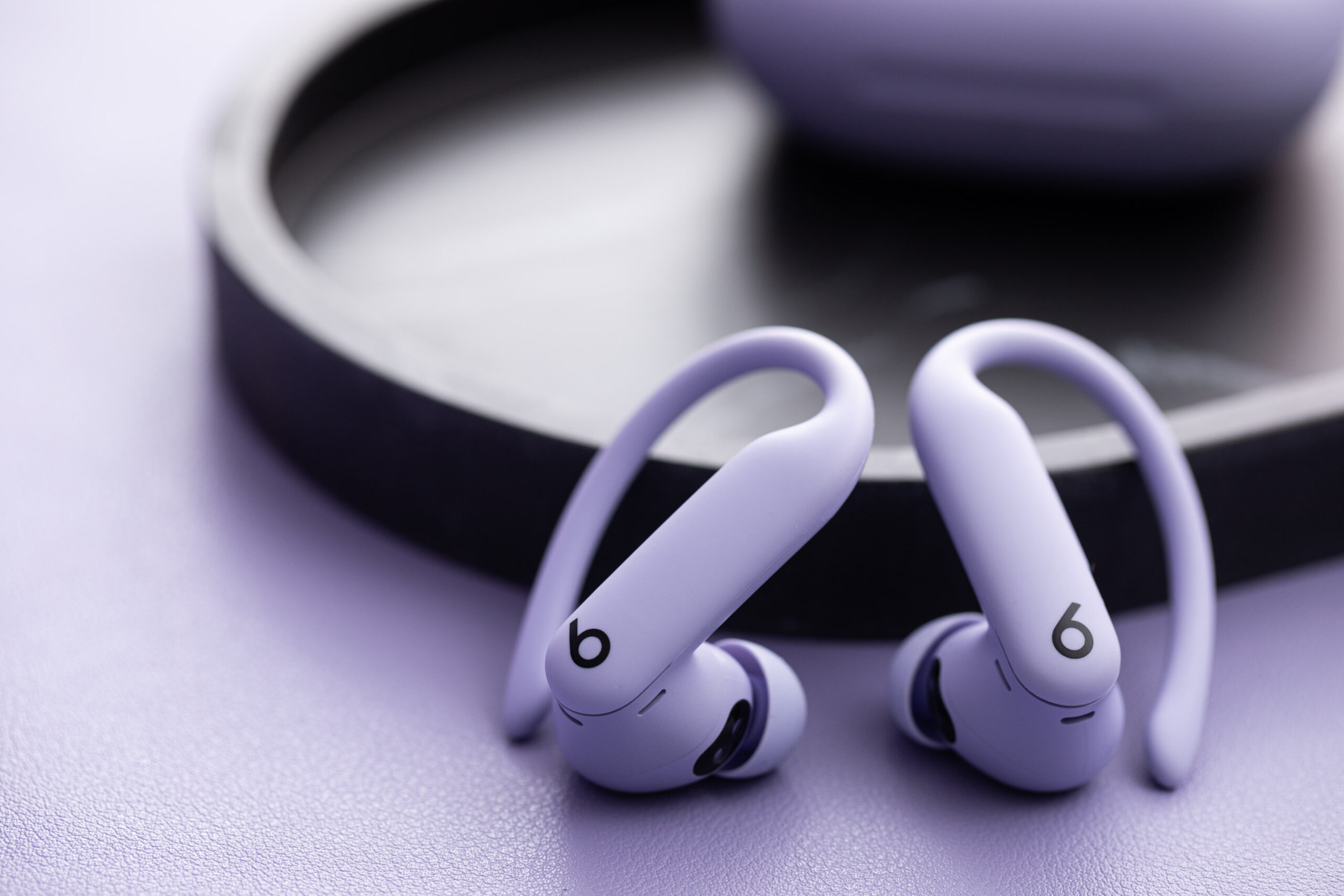 A close-up image of the Powerbeats Pro 2 in purple sitting side-by-side on a table.