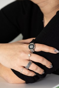 Vertical close up of Senior Reviewer Victoria Song’s hand where she wears the Casio Ring Watch on her index finger. Her other fingers have an assortment of silver rings, which are contrasted against a black shirt and holographic silver nails.