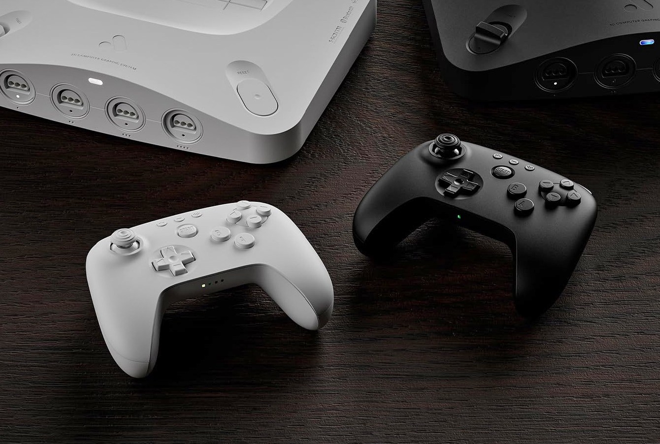 The black and white versions of the 8BitDo 64 wireless controller next to matching versions of the Analogue 3D console.
