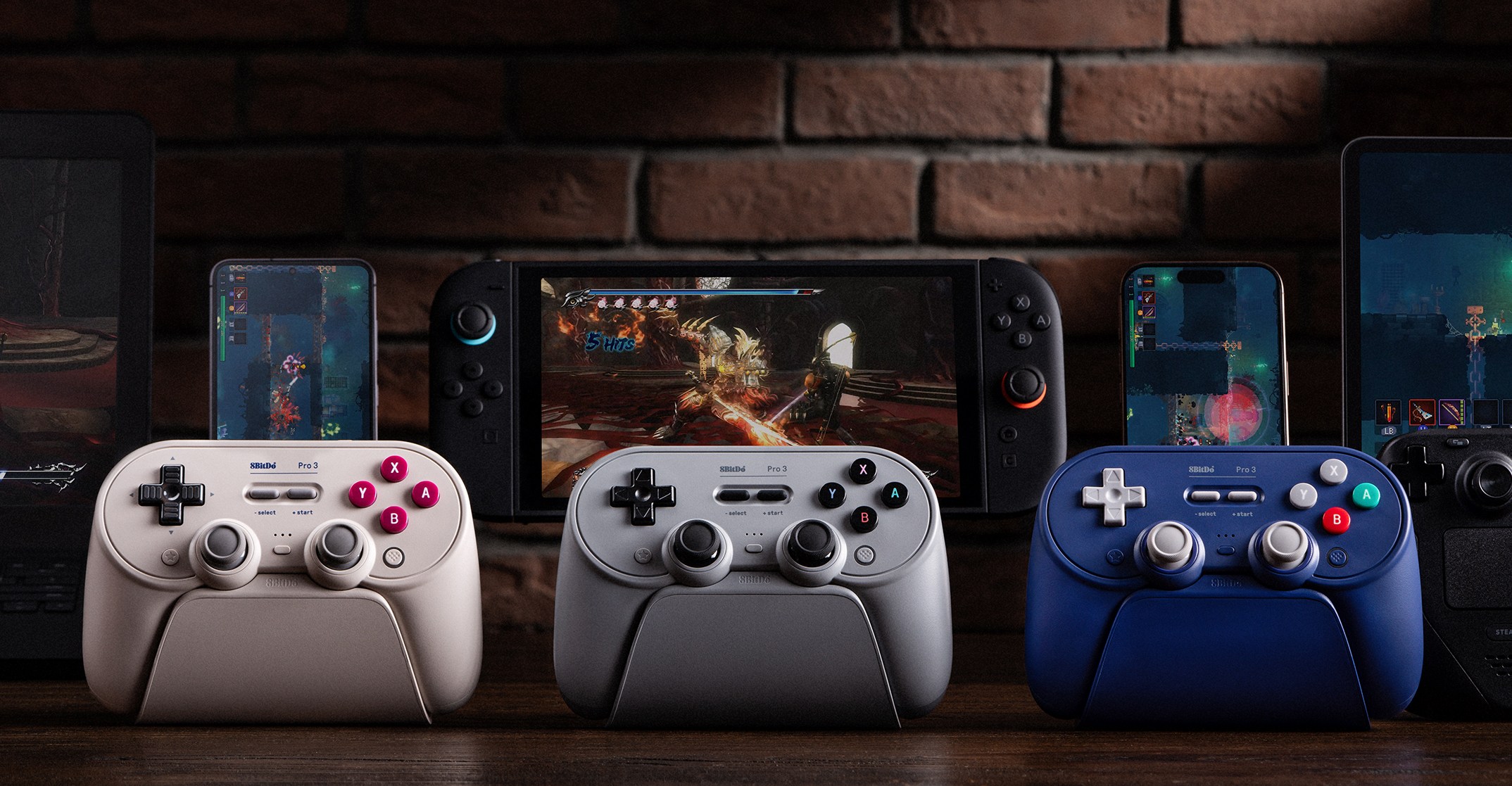 Three different versions of the 8BitDo Pro 3 wireless controller on charging docks in front of several gaming devices.