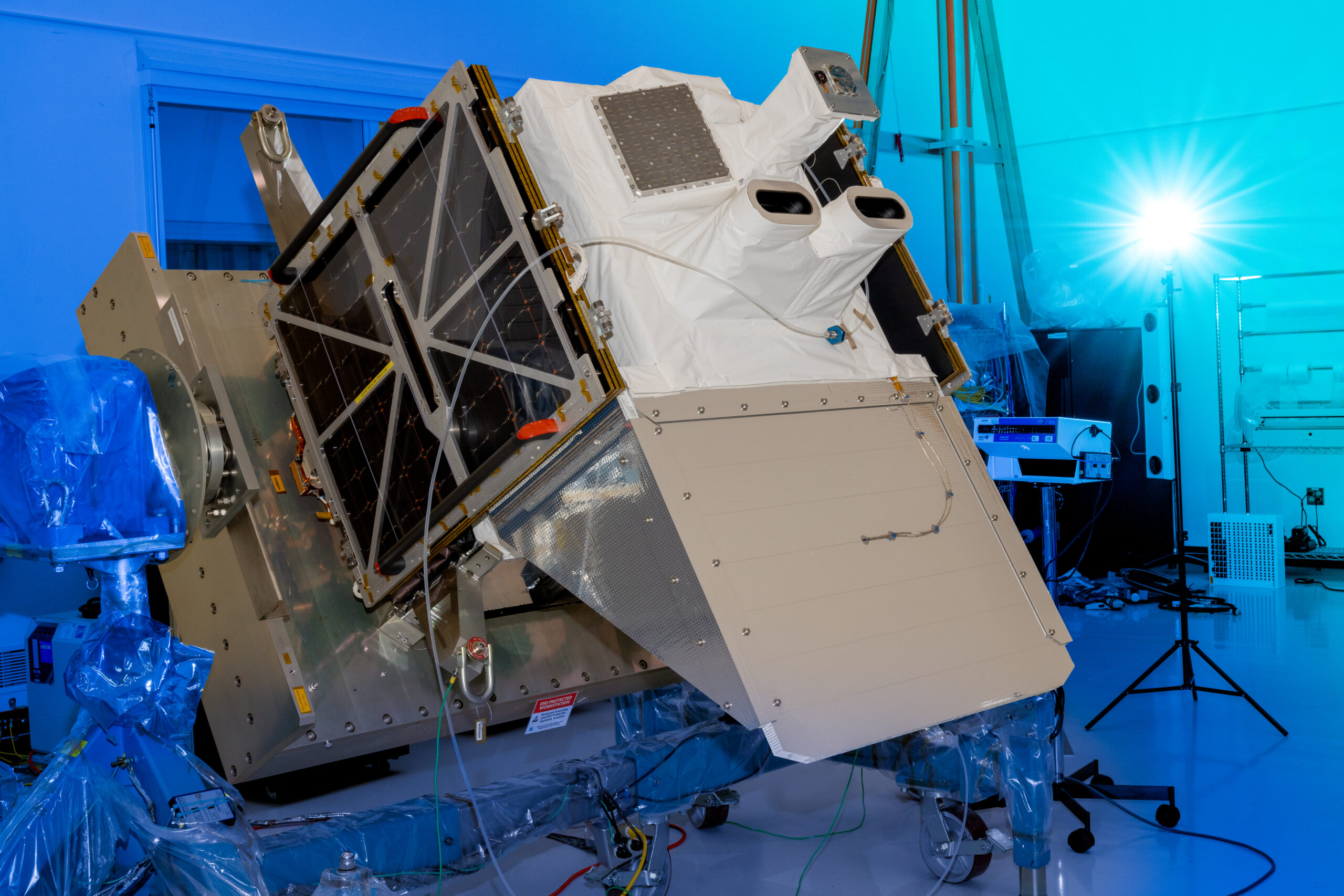 A cube-shaped satellite propped up inside a room.