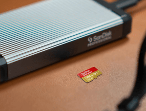 The SanDisk Extreme microSD Card (256GB) on a table next to a portable hard drive.