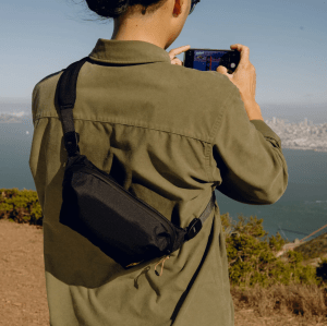 Person with camera looking out at landscape with sling across their back.