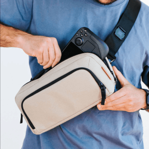 Person wearing tan sling bag and taking game controller out of it.
