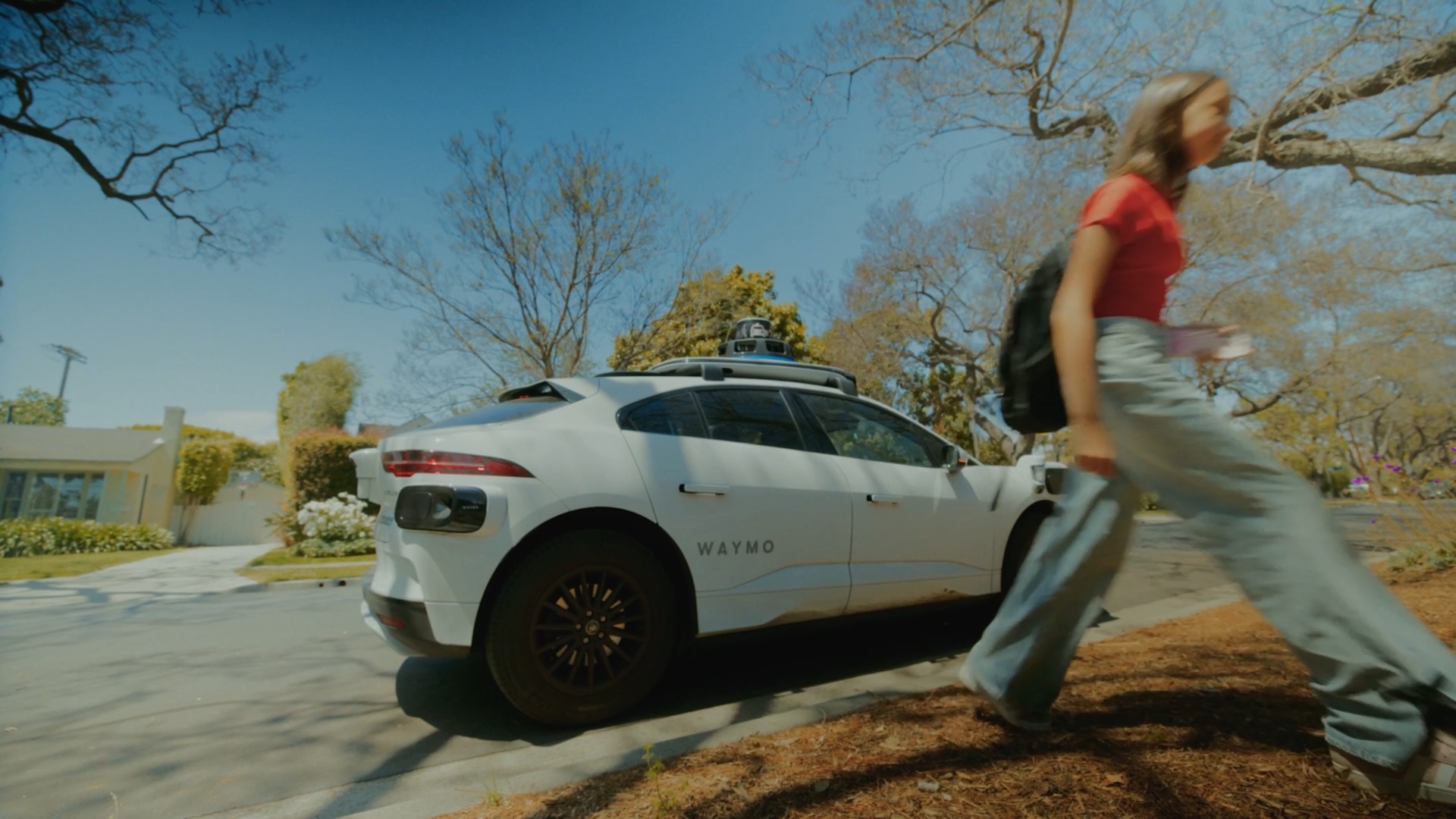 photo of teenager walking near a Waymo car