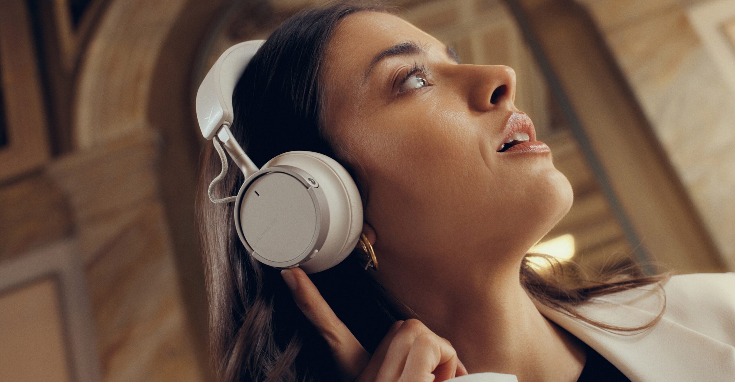 A person presses a button on one ear cup while wearing the Beyerdynamic Aventho 100 wireless headphones.