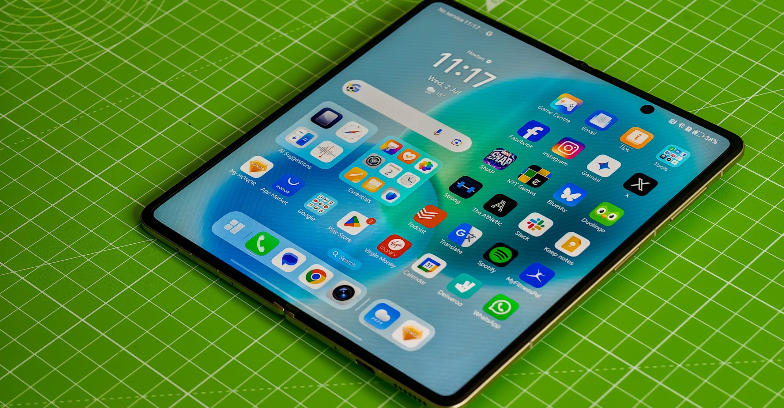 Honor Magic V5 lying flat and open on a green mat.