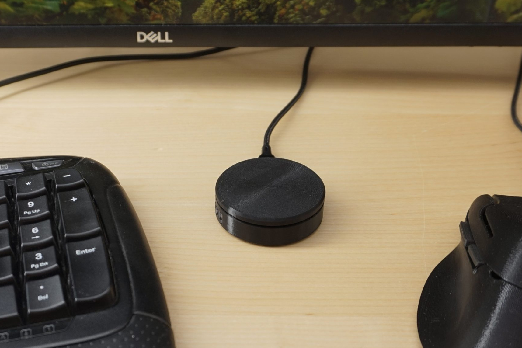 The Ploopy Knob on a wooden desk next to a keyboard, monitor, and mouse.