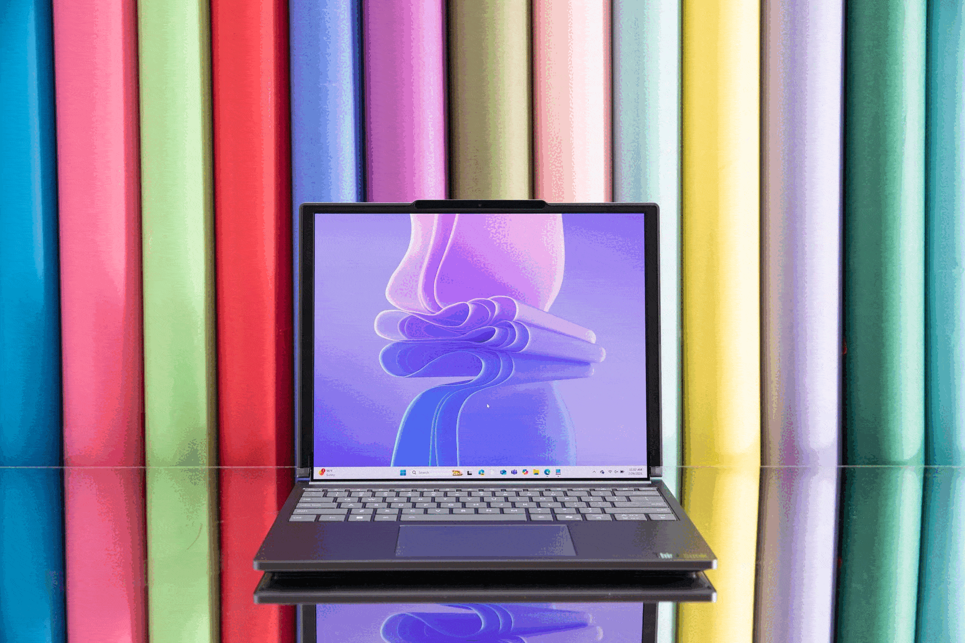An animated GIF of the Lenovo ThinkBook Plus Gen 6 laptop’s rollable display ascending upwards. It’s in front of a lineup of colorful rolls of seamless backdrop paper.