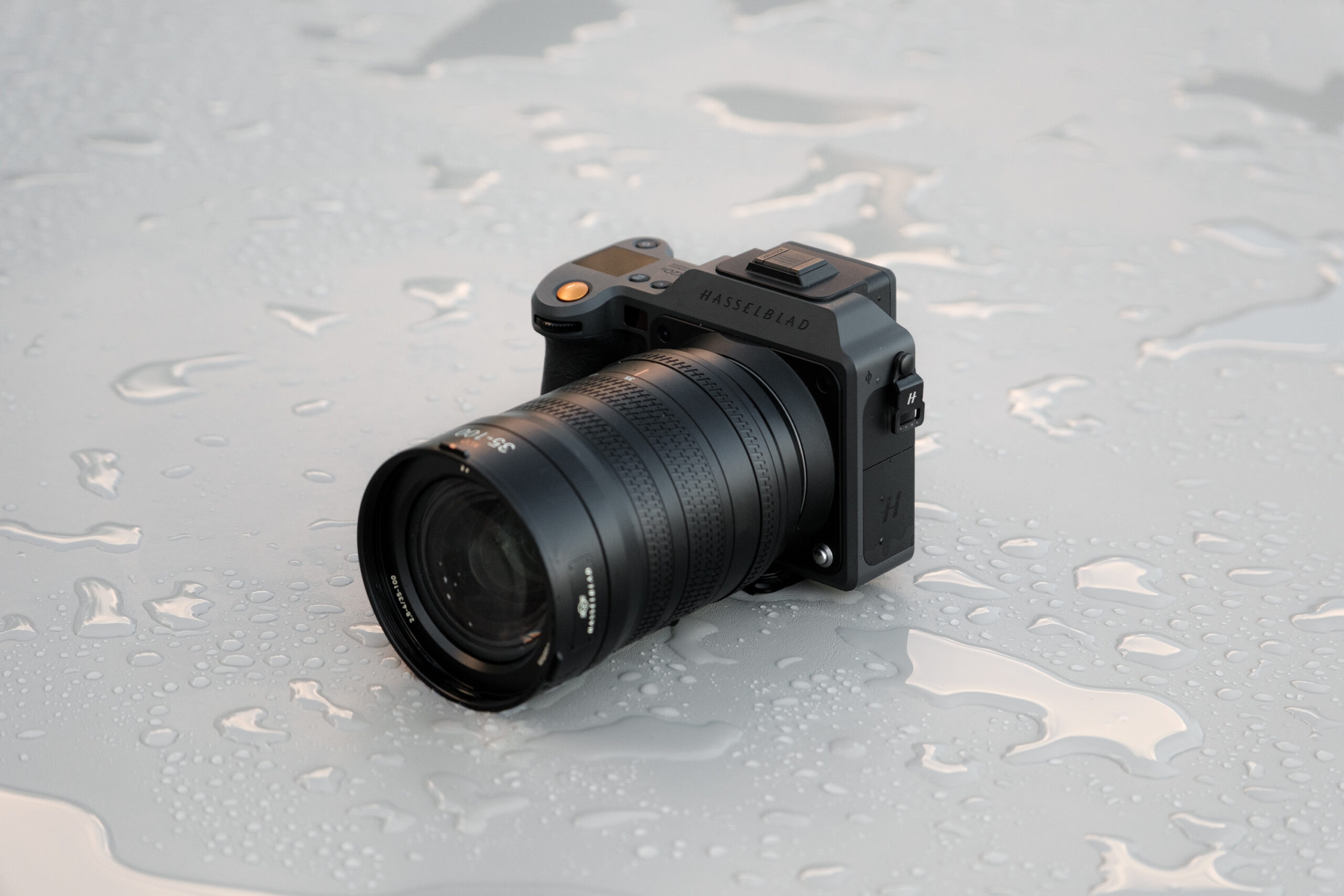 A camera sits on smooth surface with small splashes of water surrounding it.