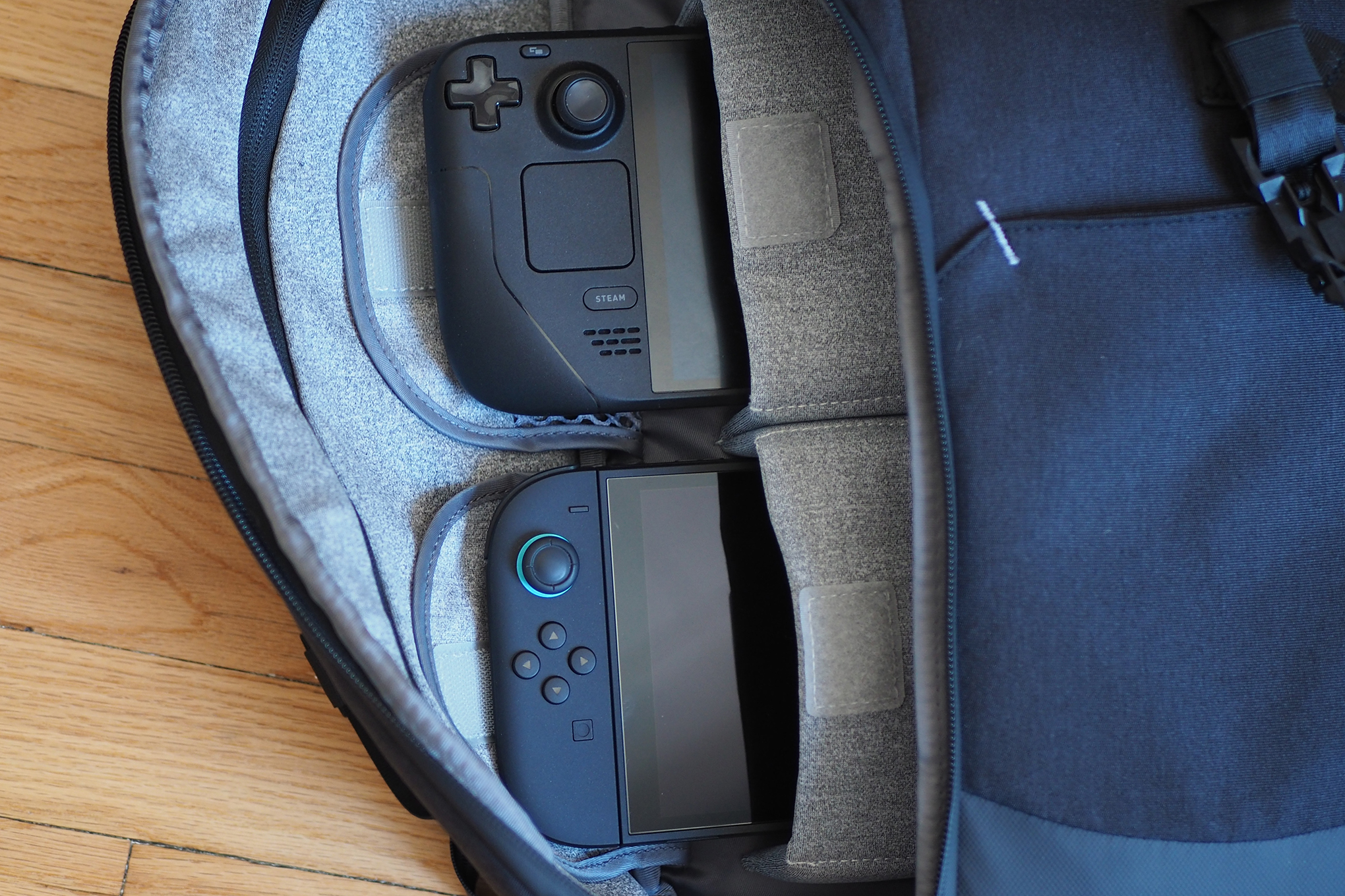 An image showing the side zipper of the CRKD Vortex 1.0 backpack opened, revealing a Steam Deck and Switch 2 tucked into its two handheld compartments.