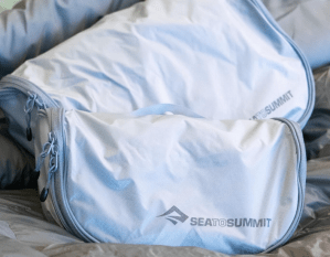 The large and small versions of the Sea to Summit Hanging Toiletry Bag sitting on a seat.