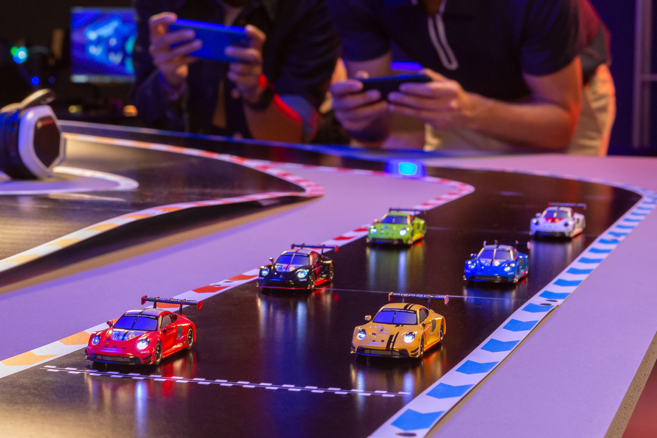 Six small RC Porsche 911 GT3 R racers lined up on a Carrera Hybrid race track.