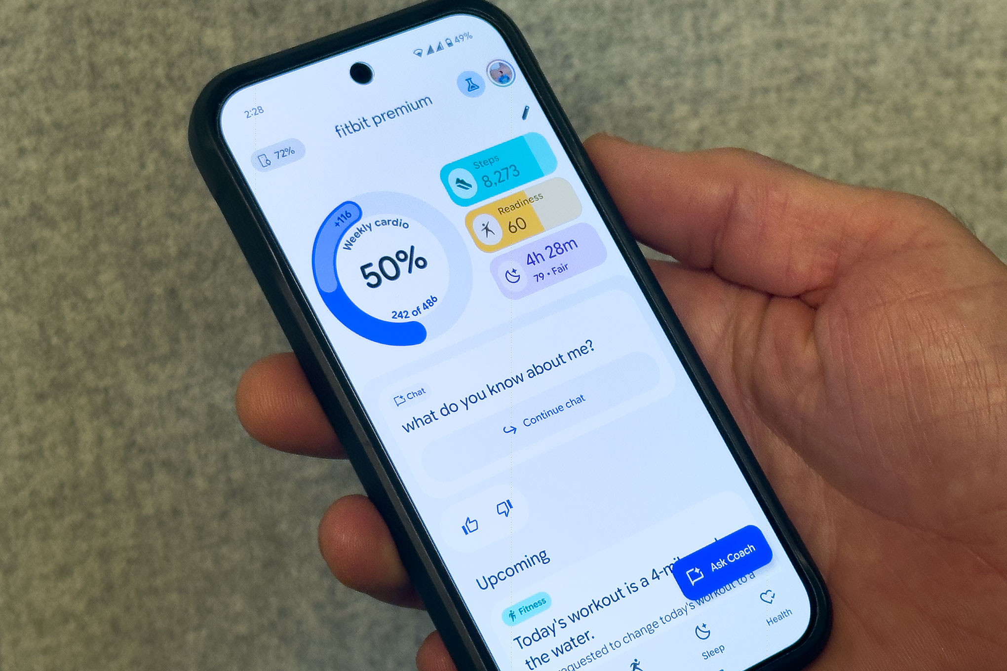 close up of a person’s hand holding a phone that shows the revamped Fitbit app showing the new AI Health coach features