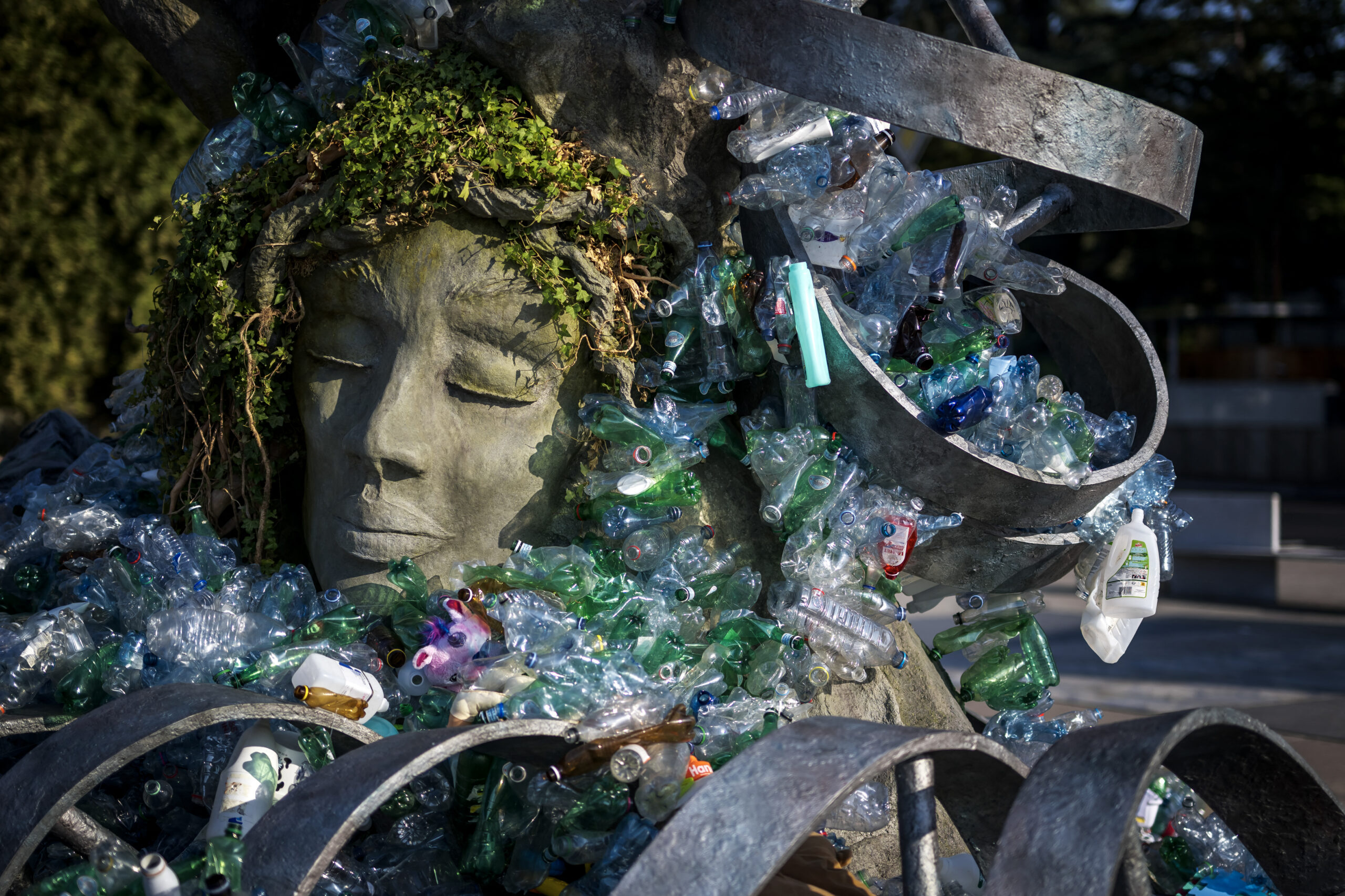 Sculptural art depicts a person’s face surrounded by plastic waste.