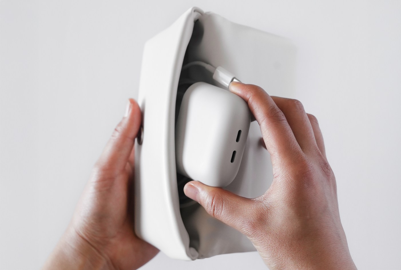 A person inserts a dual port USB-C charger into a carrying case.