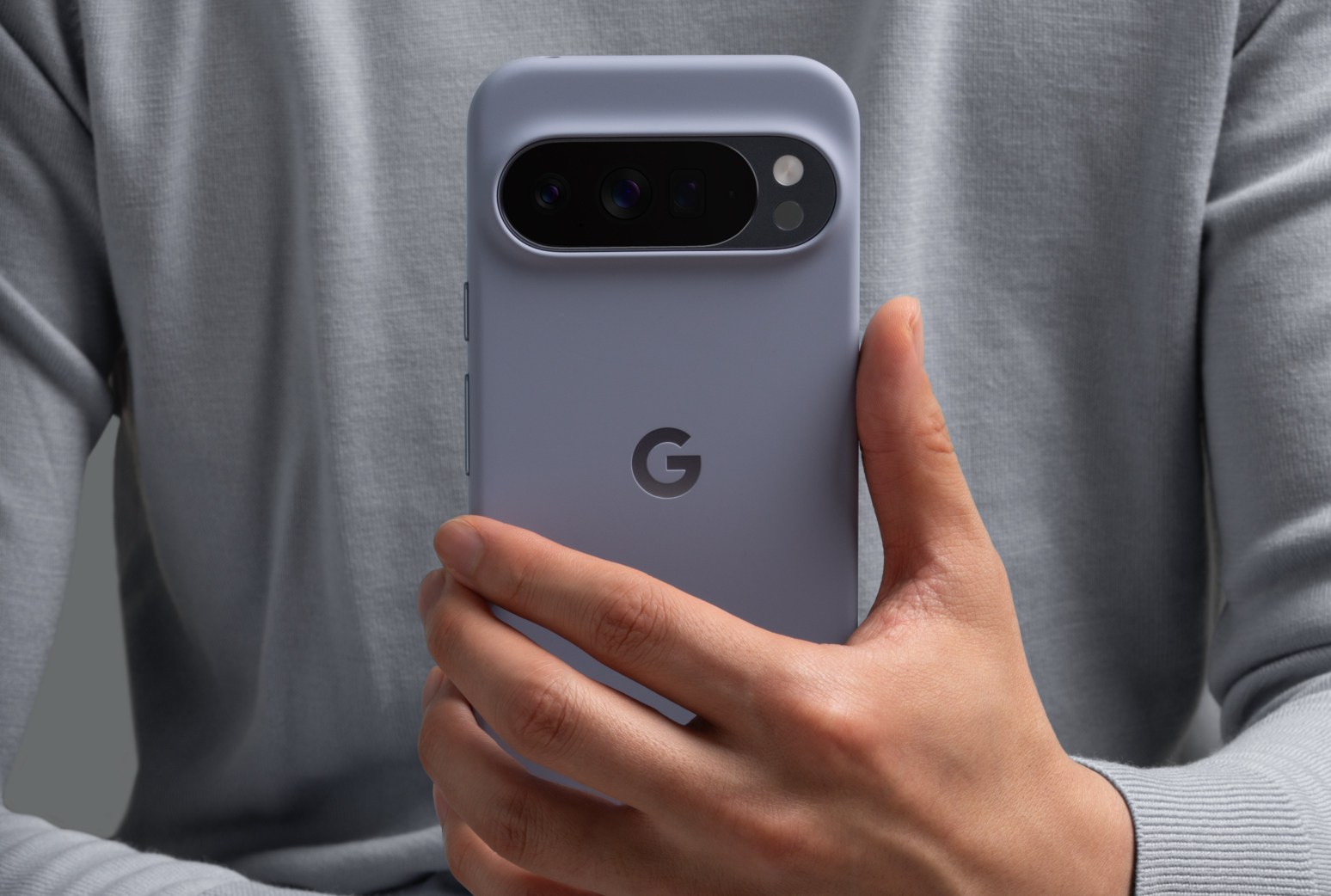 A person holds a Google Pixel smartphone inside a protective case.