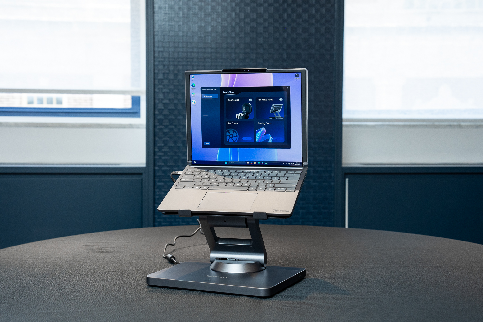 A ThinkBook Plus Gen 6 mounted on Lenovo’s Smart Motion Concept laptop stand, which is plugged into a power source and has the ThinkBook lifted into the air and tilted slightly.