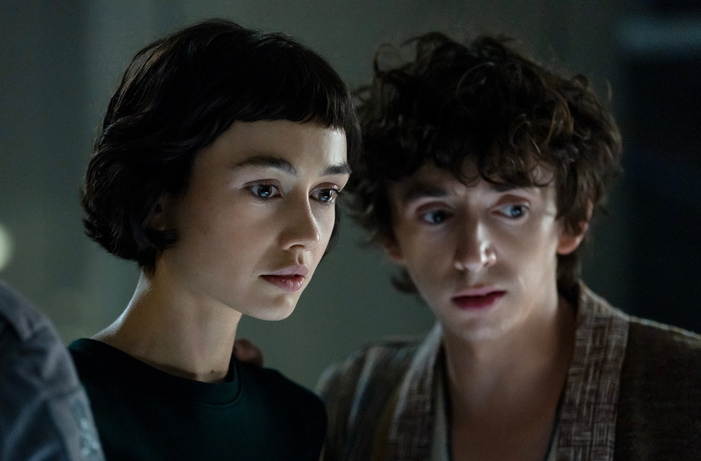 A young woman and man standing next to each other and looking at something close to the ground.