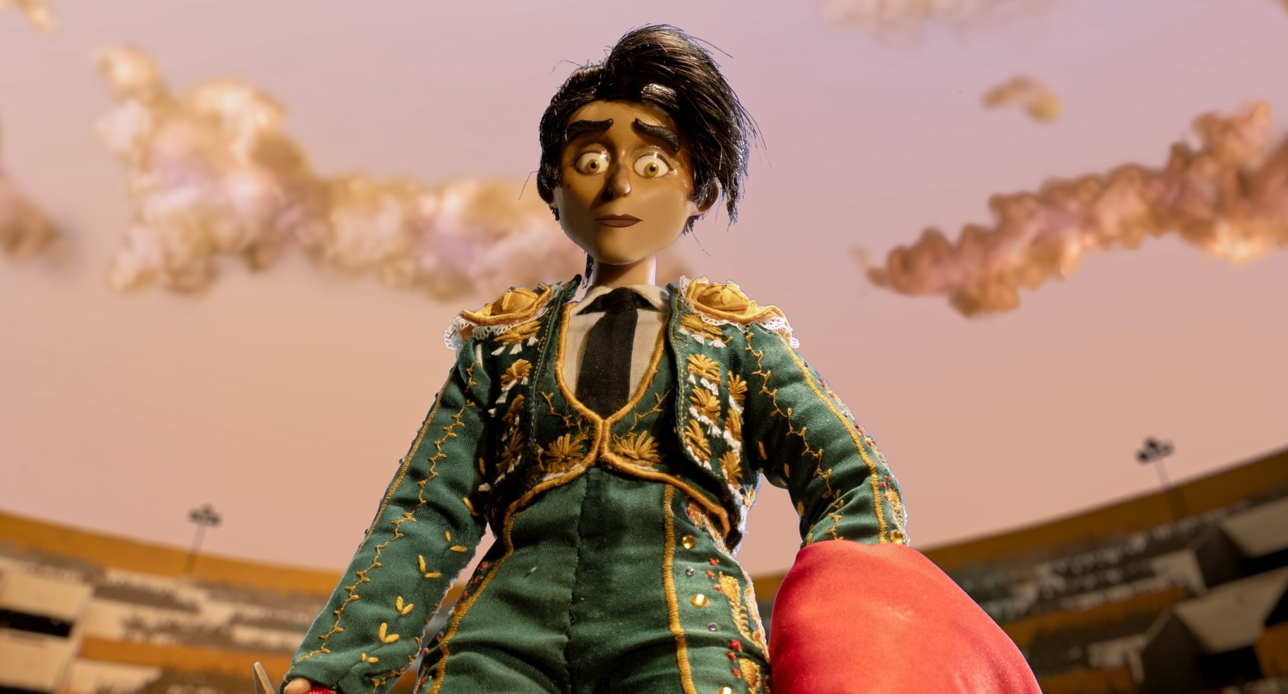 A still from a stop motion series depicting a woman in a green bullfighter’s outfit holding a red flag and looking down at the ground in shock.
