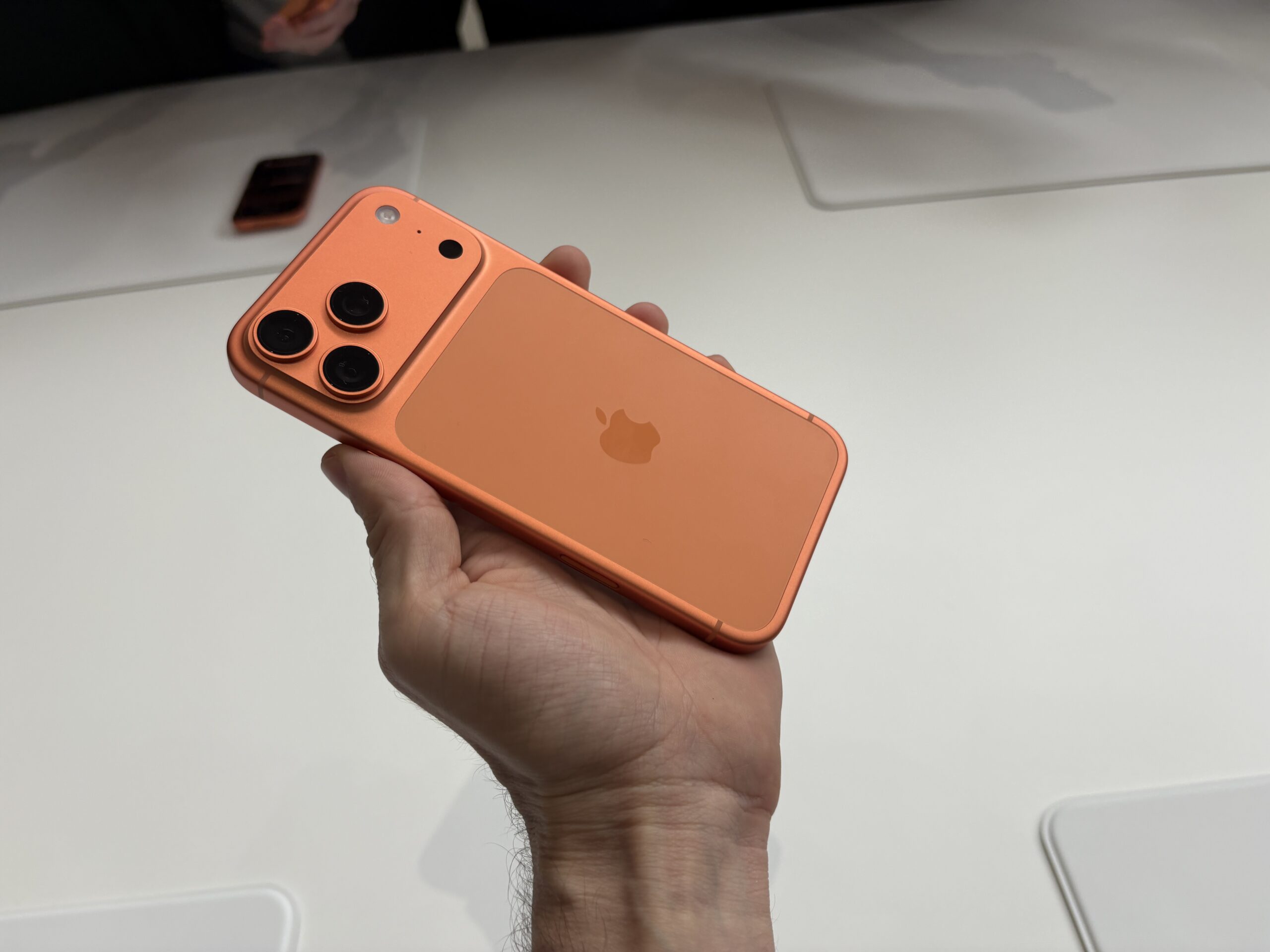An orange iPhone 17 Pro in a person’s hand.