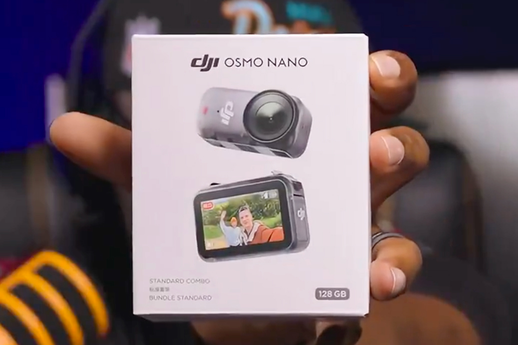 A YouTuber holds up the DJI Osmo Nano action camera in its packaging.