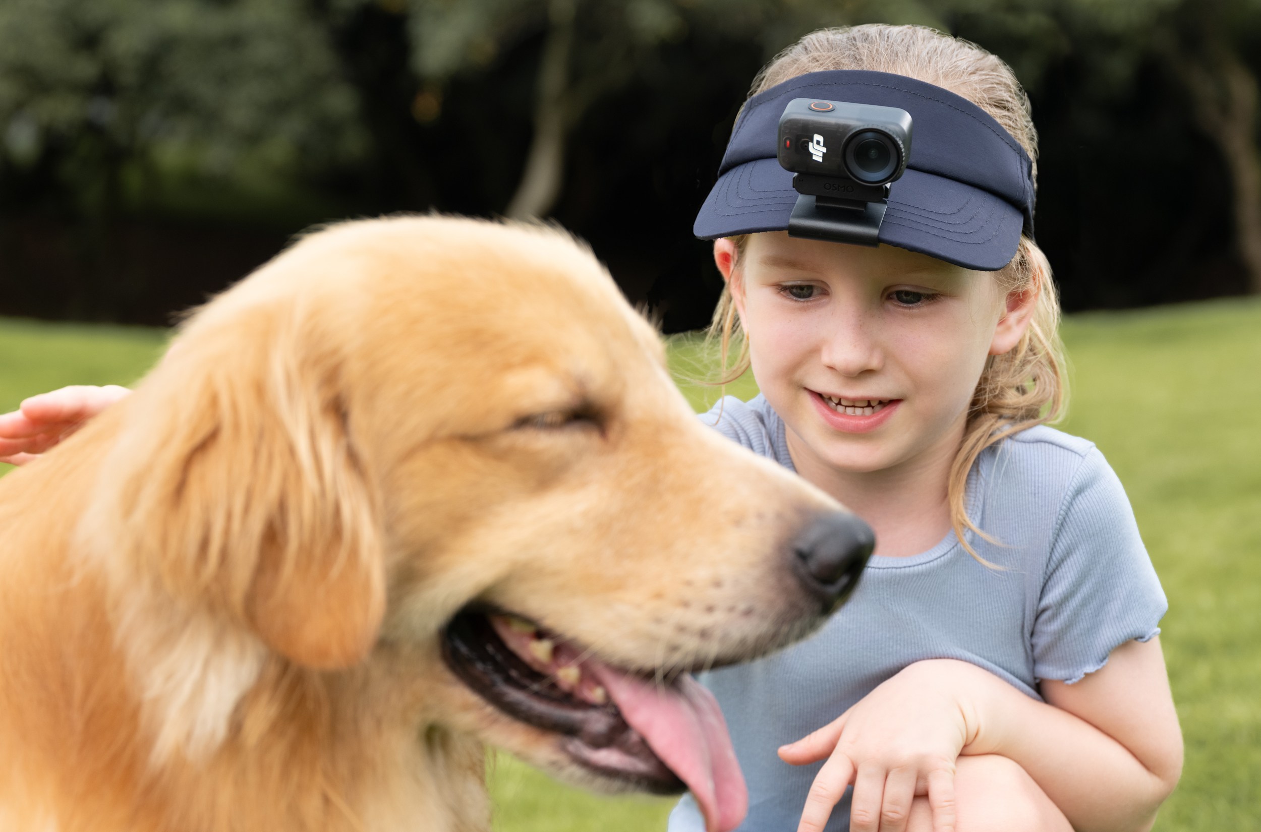 A child with the DJI Osmo Nano clipped to their hat pets a dog.